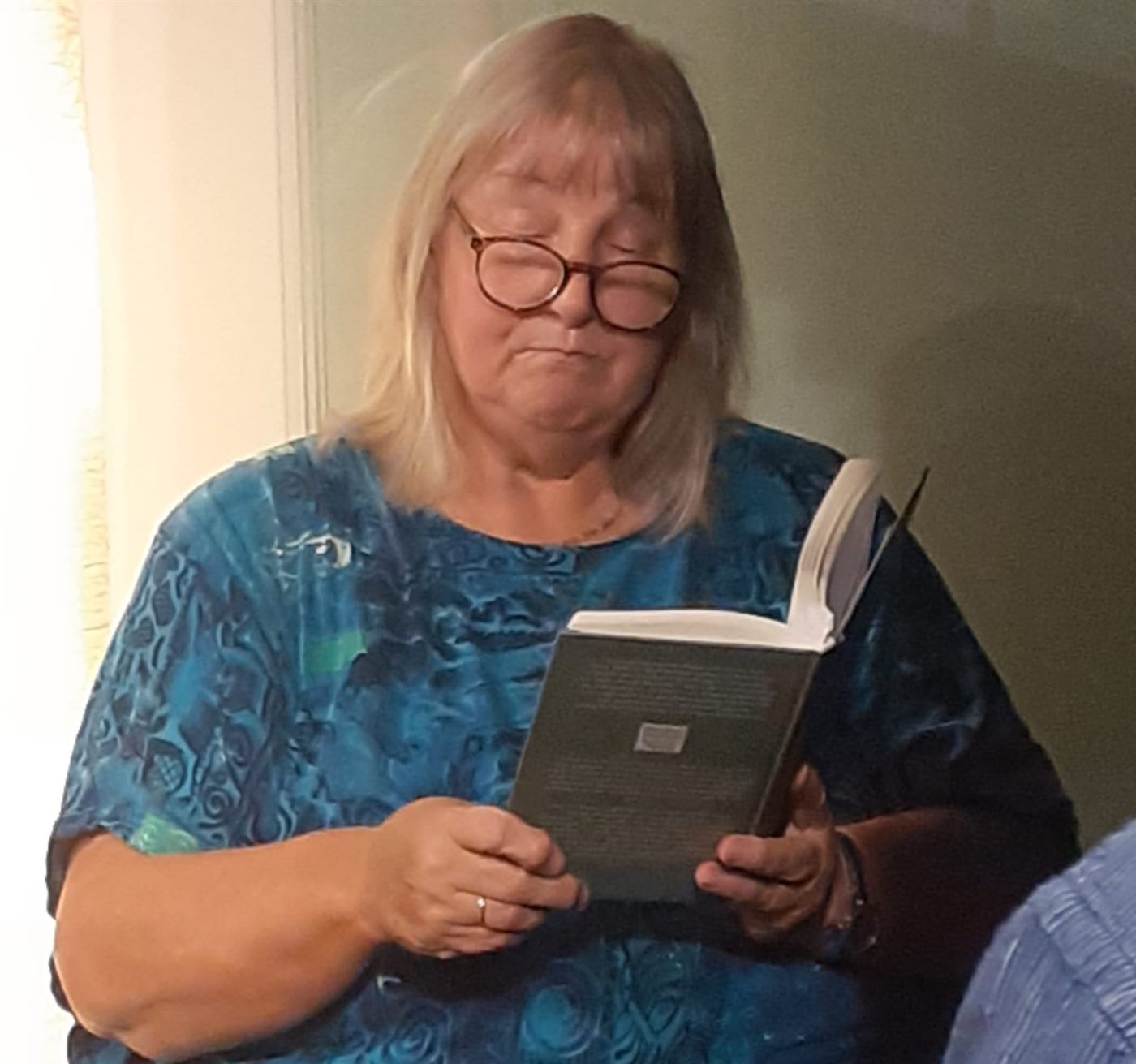 Eine Frau mit Brille liest aus einem aufgeschlagenen Buch vor